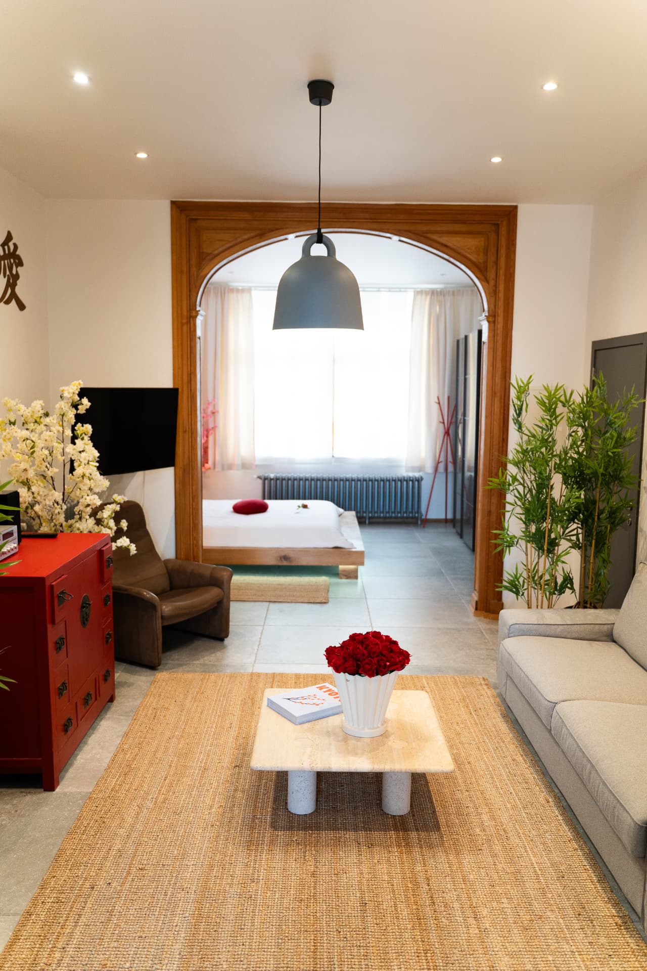 Salon de la suite avec vue sur la chambre, canapé gris et arche en bois