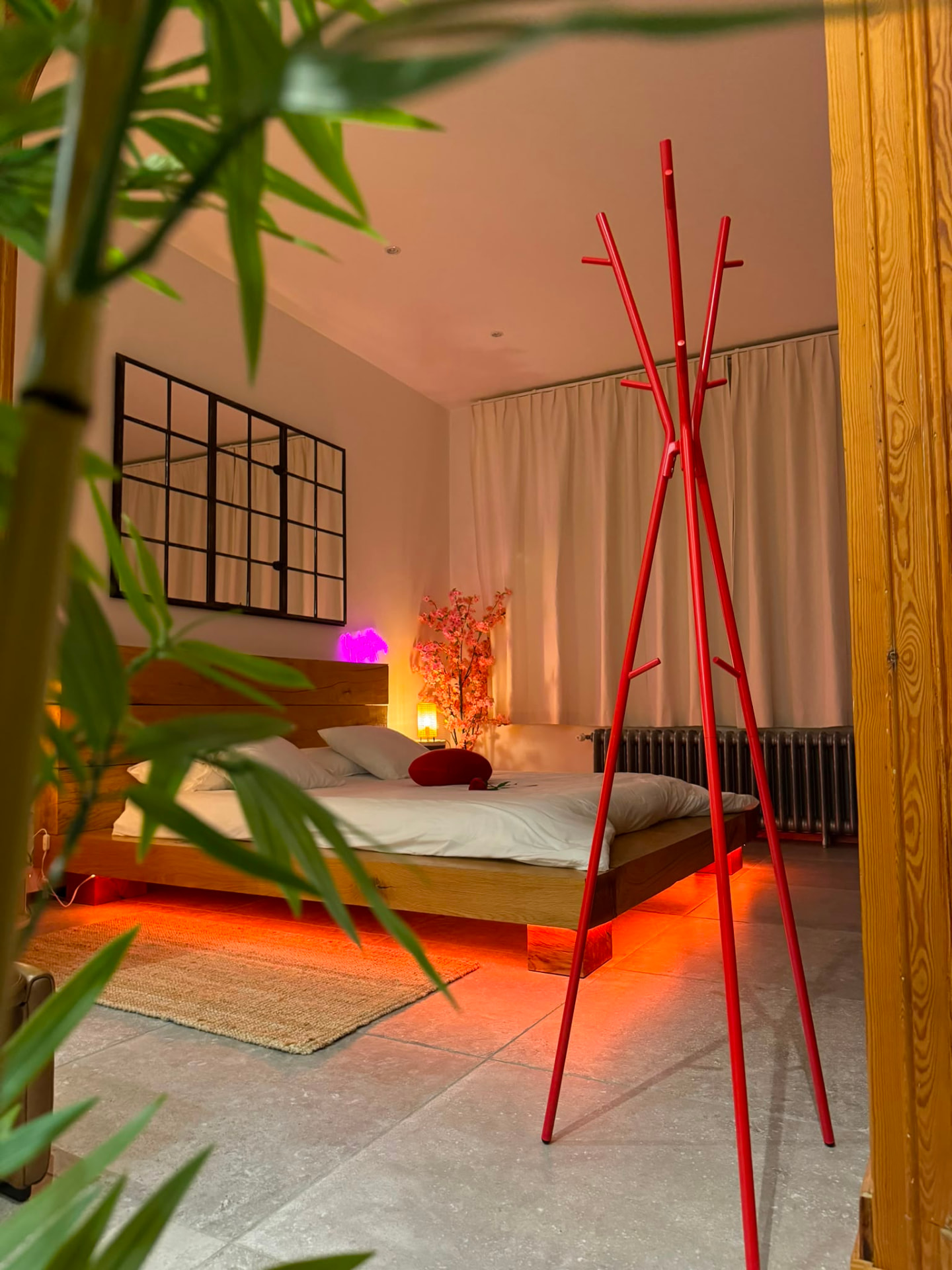 Chambre de la suite à Chimay, lumière chaleureuse et portemanteau rouge