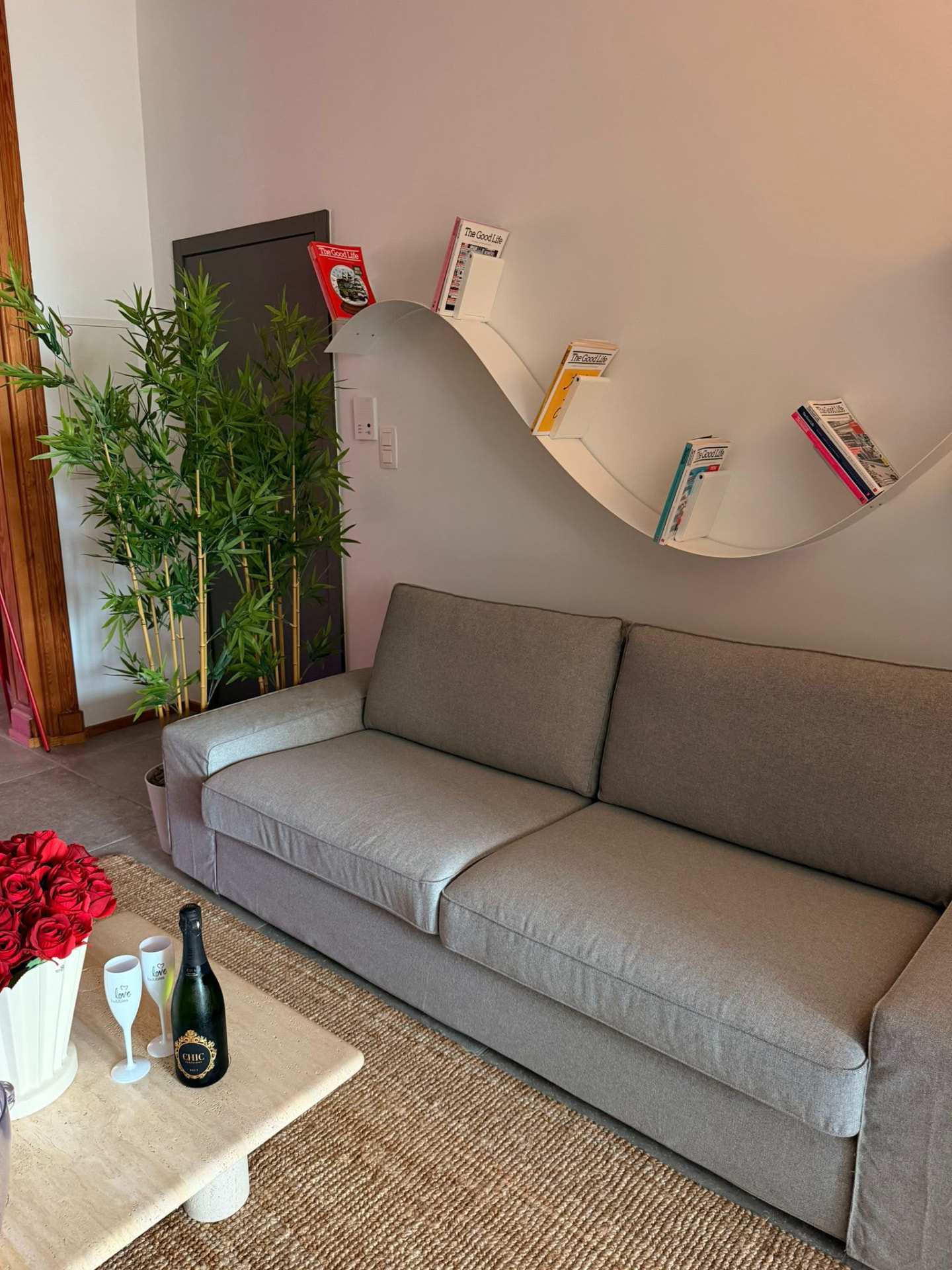 Coin salon avec champagne, roses rouges et canapé gris