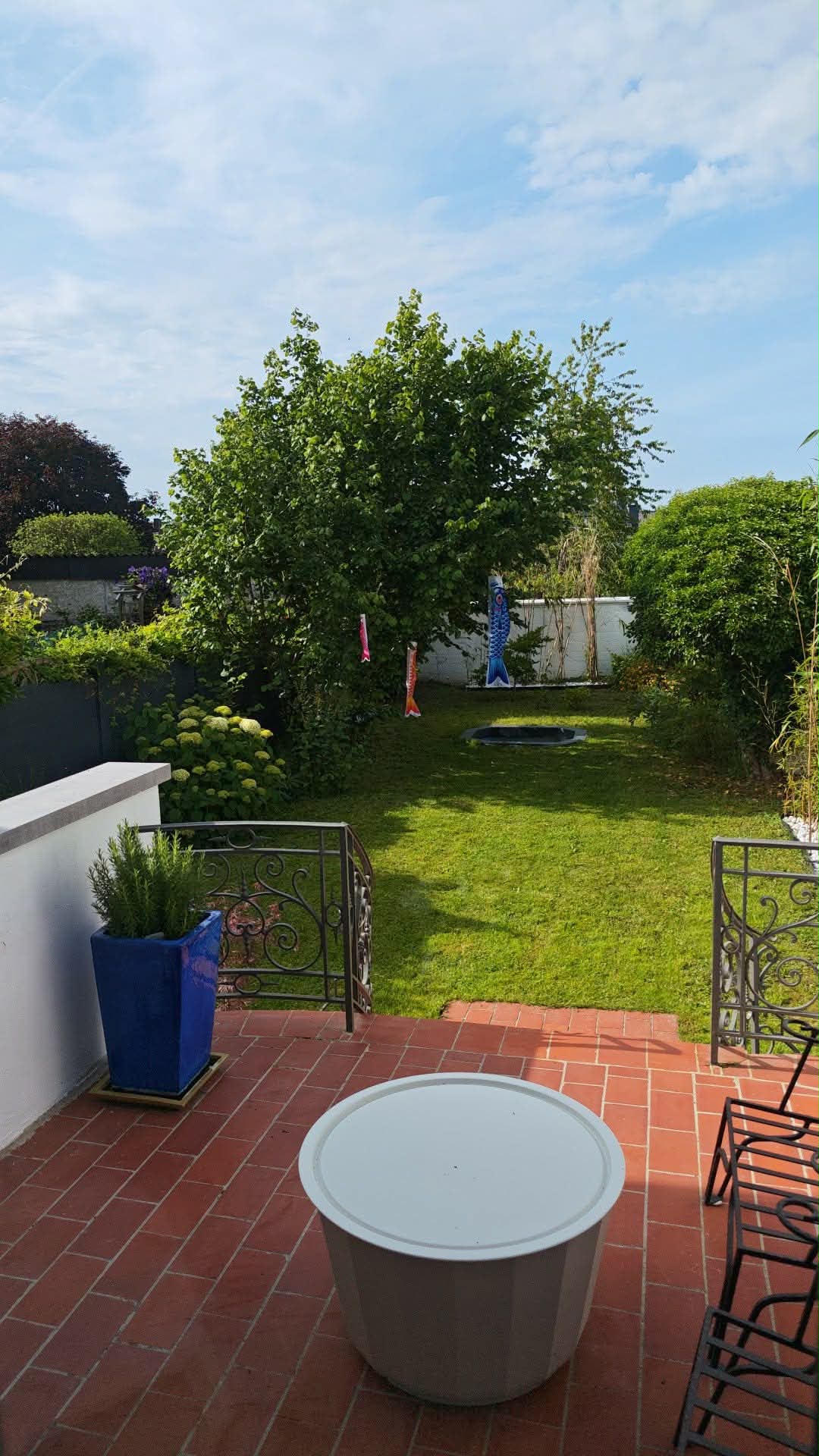 Terrasse avec carrelage rouge, koinobori et jardin verdoyant