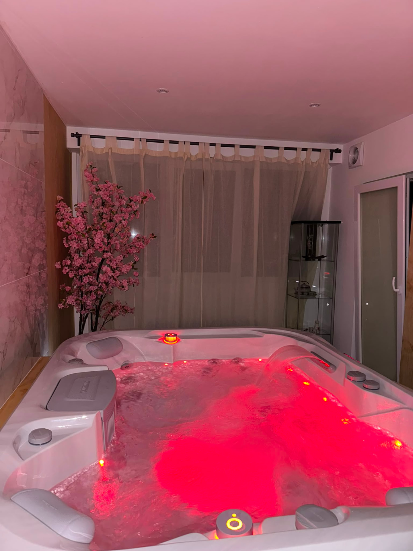 Spa romantique avec éclairage rouge et rideaux voilés