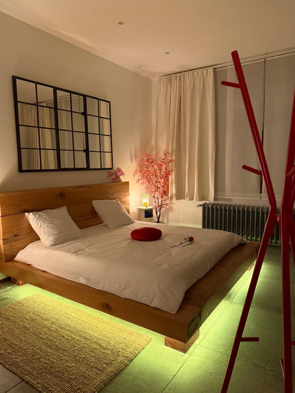Chambre avec éclairage vert sous le lit et décoration romantique