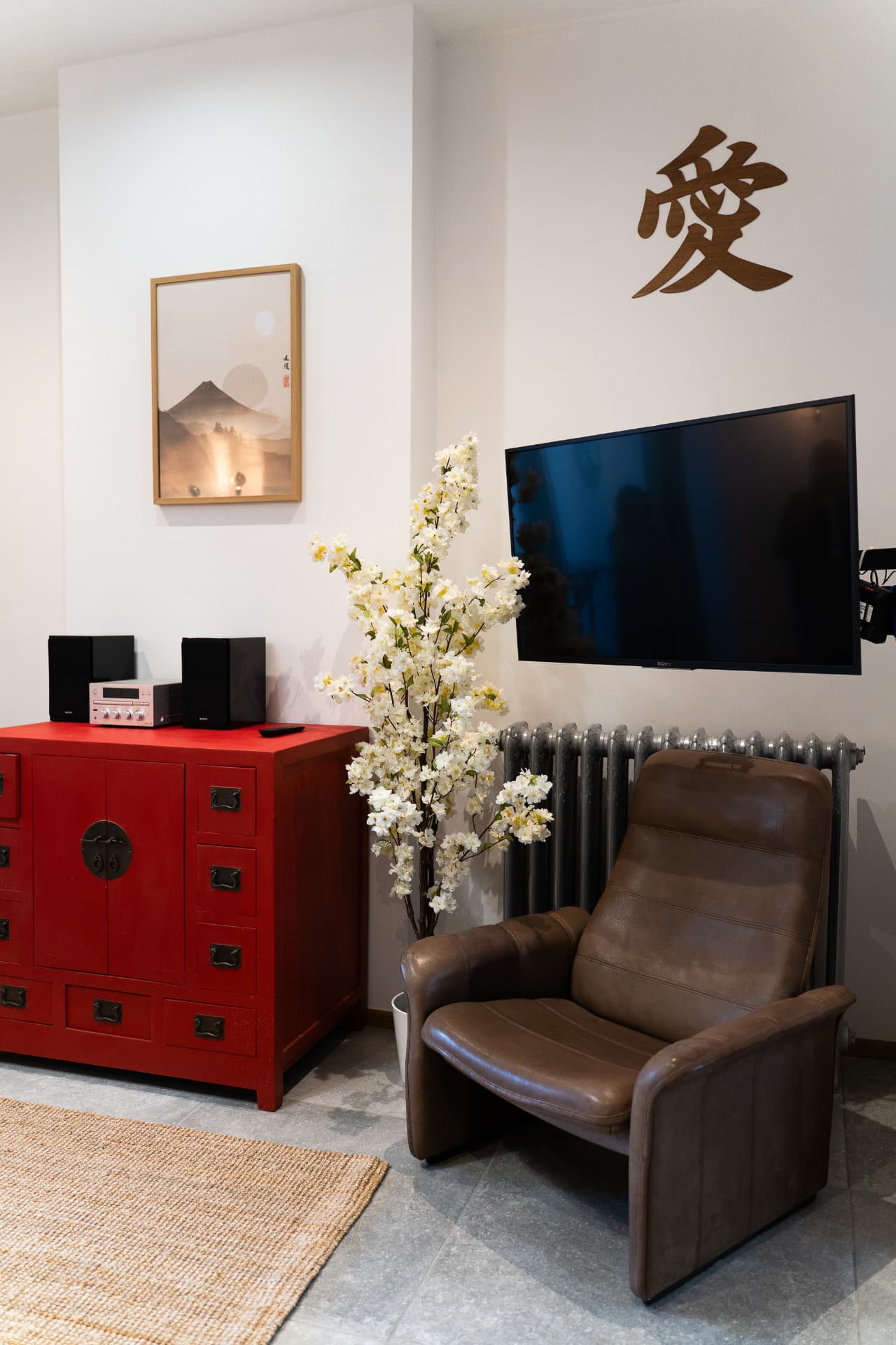 Coin détente du salon, fauteuil en cuir, meuble rouge et télévision